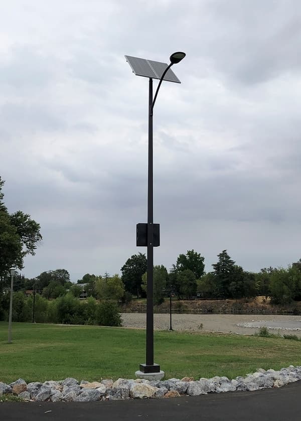 A solar street light pole beside a path at dusk