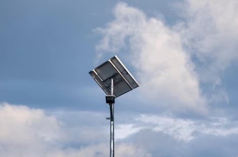 Solar LED light fixture on a pole with sun in the background