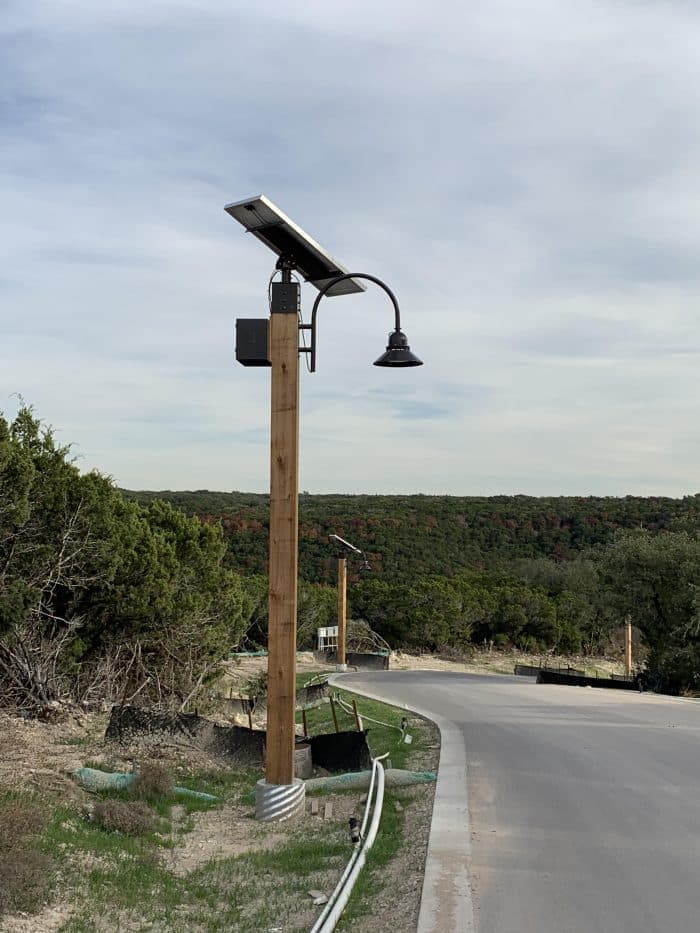 Lumina solar light system mounted on a wood pole, showing the battery housing